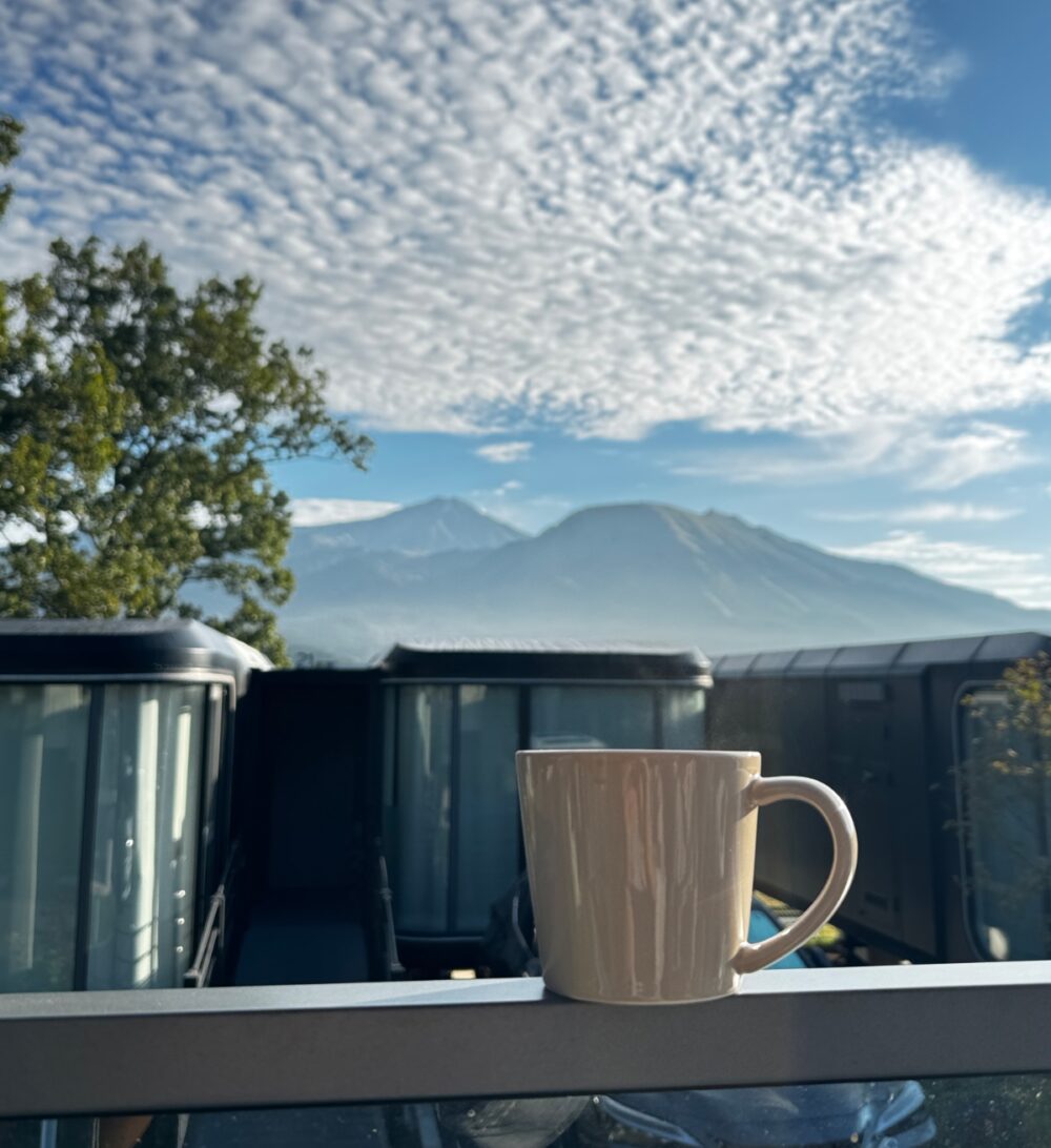 朝の阿蘇の山々を背景にしたコーヒーカップ