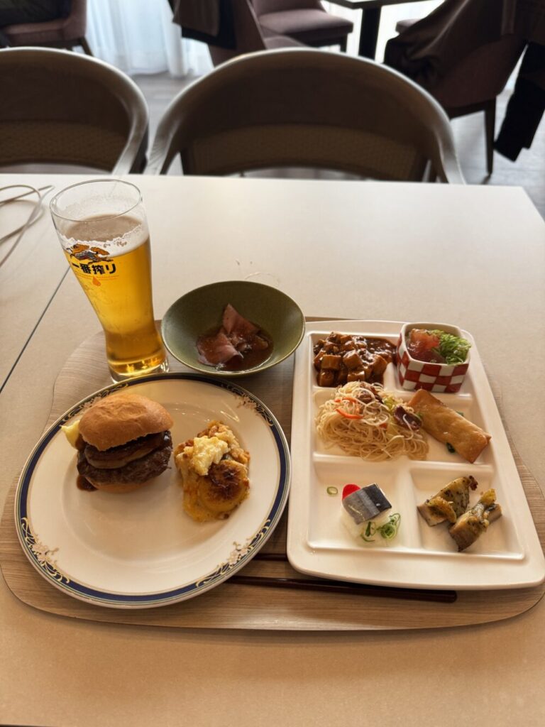 夕食ビュッフェでお皿に取ったバーガーや料理とビール
