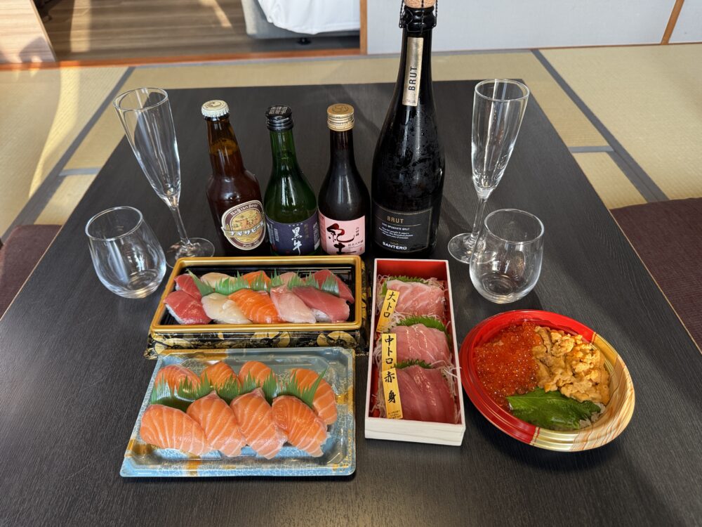 和洋室の座卓に並べた寿司、海鮮丼、日本酒やワイン